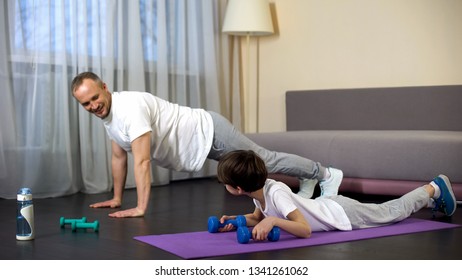 Serious Sportive Family Doing Plank Exercise With Dumbbells At Home, Role Model