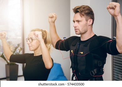 Serious Sportsman Working Out With Personal Coach At Gym