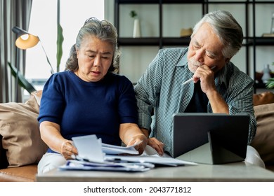 Serious Stressed Asian Senior Old Couple Worried About Bills Discuss Unpaid Bank Debt Paper, Sad Poor Retired Family Looking At Tablet Counting Loan Payment Worry About Money Problem