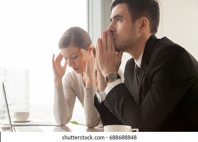 Serious stressed businessman thinking hard how to solve problem while worried businesswoman trying to concentrate, preparing to important negotiations, facing business challenge, company bankruptcy - Powered by Shutterstock