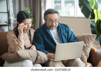 Serious Stressed Middle-aged Asian Couple Finances Calculate Bills Tax On The Laptop.