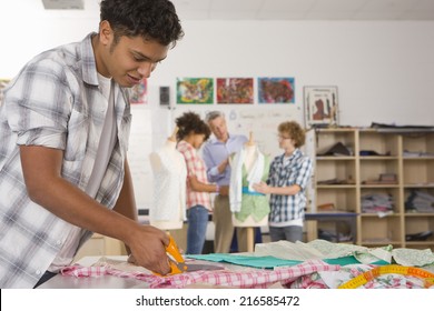 Serious Student Cutting Fabric In Home Economics Classroom