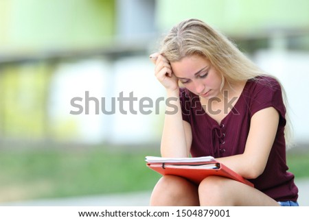 Serious student studying memorizing notes sitting outdoors in an university campus