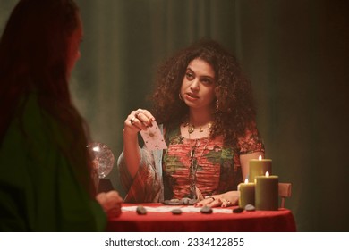 Serious tarot cards reader talking to client and giving her advice on problem