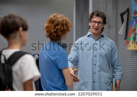 Serious teacher communicating with schoolboys at the recess [[stock_photo]] © 