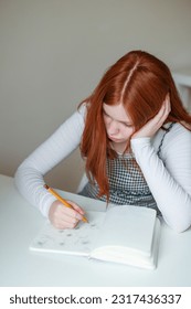 Serious teen girl school pupil draw alone sitting at kitchen table  