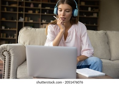 Serious Teen Millennial Student Girl In Big Headphones Studying From Home, Watching Learning Webinar, Virtual Training, Online Conference On Laptop, Chatting, Talking On Video Call