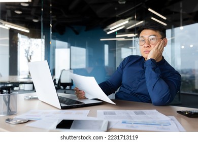 Serious thinking asian man working with documents inside office, concentrated businessman with contracts and bills reading and calculating reports, mature financier with documents. - Shutterstock ID 2231713119