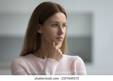 Serious Thoughtful 30s Woman In Casual Standing Indoors, Looking Away, Touching Chin, Thinking, Feeling Uncertain, Doubtful, Concerned. Pretty Adult Lady With Natural Makeup Candid Portrait