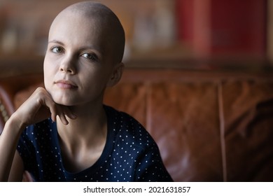 Serious Thoughtful Ill Hairless Cancer Patient Portrait. Skinny Pale Woman With Shaved Head, Disease Fighter Sitting On Couch At Home, Looking At Camera. Oncology At Young Age. Head Shot