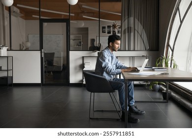 Serious thoughtful Indian businessman, male office employee analyzing data, or writing emails, working on task using laptop, sit alone in corporate workspace. Productivity, focus, and professionalism - Powered by Shutterstock