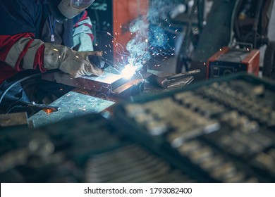 Serious welder working in manufactory and wearing protective mask while using blowtorch - Powered by Shutterstock