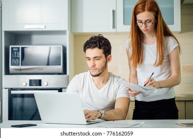 Serious woman calculate or write accounts with pen, her husband using laptop and checks her results - Shutterstock ID 776162059