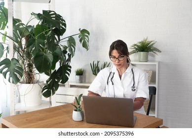 Serious Woman Doctor Talking To Patient On Laptop Video Call From The Hospital Office. Female Health Care Worker Telling Bad News To The People Of Deceased Family Member Over Webcam From The Clinic.