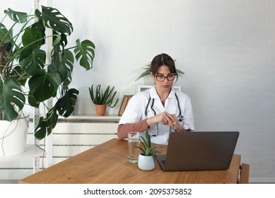 Serious Woman Doctor Talking To Patient On Laptop Video Call From The Hospital Office. Female Health Care Worker Telling Bad News To The People Of Deceased Family Member Over Webcam From The Clinic.