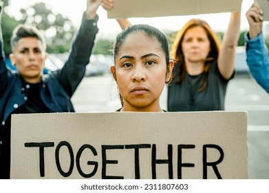 Serious woman in group of others with protesting cardboard - Shutterstock ID 2311807603
