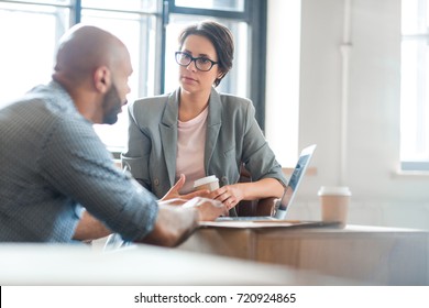 Serious woman listening to co-worker explaining new online business trends - Shutterstock ID 720924865