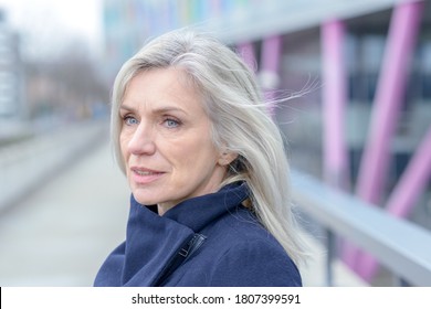 Serious woman looking intently to the side with a thoughtful expression as she stands outdoors in town on a walkway - Powered by Shutterstock