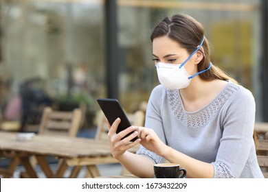 Serious woman with protective face mask looking at smart phone checking news on a cafe terrace - Powered by Shutterstock