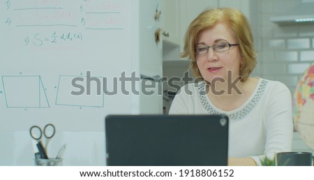 Serious woman is talking by video call on tabletPC, teacher is communicating with student online during pandemic of coronavirus. Distance Learning, e-education, e-Learning, homeschooling concept.