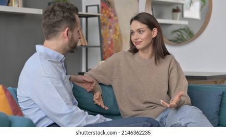 Serious Woman Talking To Man While Sitting On Sofa 