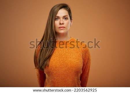 Serious woman with unemotional face isolated portrait on orange background.