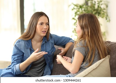 Serious Women Talking Sitting On A Couch In The Living Room At Home