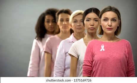 Serious women wearing pink breast cancer awareness ribbons standing in row