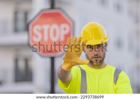 Serious worker with stop road sign. Builder with stop gesture, no hand, dangerous on building. Man in hard hat helmet doing stop sign with serious and confident expression, defense gesture.