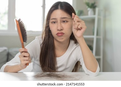 Serious, Worried Asian Young Woman, Girl Holding Brush, Show Her Comb, Hairbrush With Long Loss Hair Problem After Brushing, Hair Fall Out On Her Hand In Living Room. Health Care, Beauty Treatment.