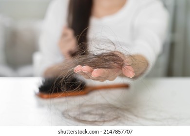 Serious, Worried Asian Young Woman, Girl Holding Brush, Show Her Comb, Hairbrush With Long Loss Hair Problem After Brushing, Hair Fall Out On Her Hand In Living Room. Health Care, Beauty Treatment.