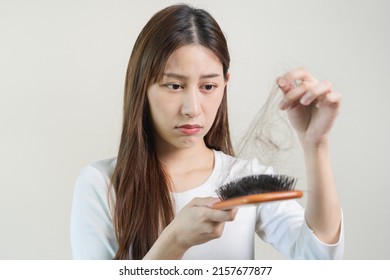 Serious, Worried Asian Young Woman, Girl Holding Brush, Show Her Comb, Hairbrush With Long Loss Hair Problem After Brushing, Hair Fall Out On Her Hand In Living Room. Health Care, Beauty Treatment.