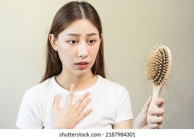 Serious, worried asian young woman, girl holding comb, show her hairbrush with long loss hair problem after brushing, hair fall out problem. Health care, beauty with copy space on white background. - Shutterstock ID 2187984301