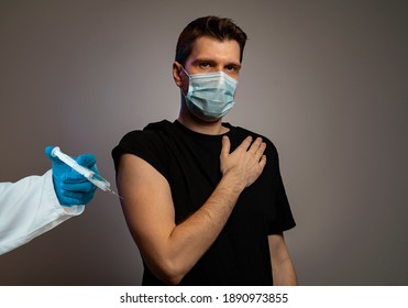 Serious Young Adult Man, Getting Flu Shot, Wearing Face Mask. Coronavirus Vaccine Concept