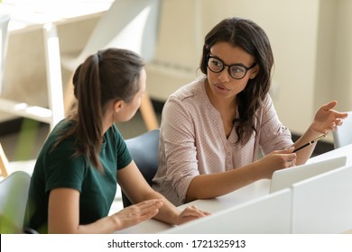 Serious young african american businesswoman talking with female leader in boardroom at meeting. Confident diverse mentor with glasses presenting new business concept with woman colleague discuss.