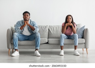 Serious Young African American Couple Sitting Separate On The Couch At Home, Looking At Camera, Guy And Lady Offended After Quarrel Not Talking To Each Other Having Relationship Problems Crisis