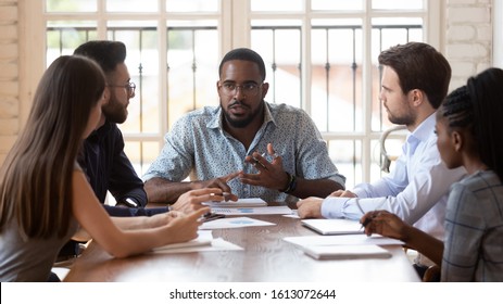 Serious young african American male ceo or boss lead office meeting with multiethnic colleagues, diverse coworkers gather in boardroom brainstorm discuss business ideas consider project together - Shutterstock ID 1613072644