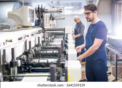 Serious young bearded employee of printing plant in blue overall working with modern machine - Powered by Shutterstock