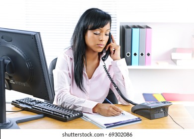 Serious Young Black Business Woman On Phone Taking Notes In Office