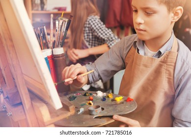 Serious Young Boy Painting On Art Canvas