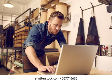 Serious Young Business Owner Using Laptop In His Workshop