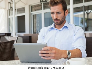 Serious young businessman working on tablet pc in patio of restaurant - Shutterstock ID 176513516