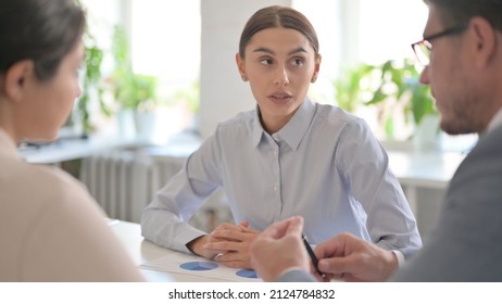 Serious Young Businesswoman Talking To Male And Female Business Person