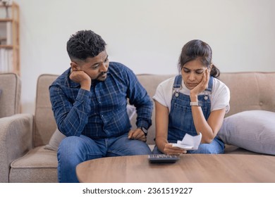Serious young couple indian together, have serious looks, plan their budget, do paperwork, busy preparing financial report, calculate debt bill - Shutterstock ID 2361519227