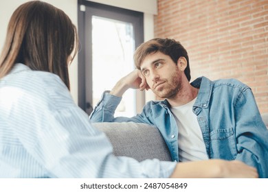 Serious young couple sitting together on sofa, talking about relationships, spending time together at home, focused wife listening to speaking husband, friends having conversation - Powered by Shutterstock