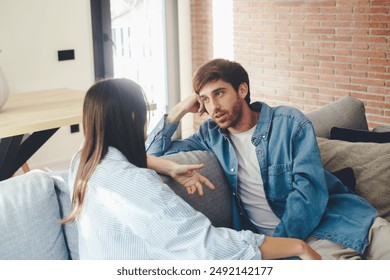 Serious young couple sitting together on sofa, talking about relationships, spending time together at home, concentrated husband listening to wife talking, friends having conversation - Powered by Shutterstock