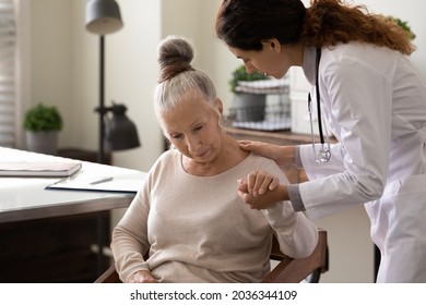 Serious young doctor helping elder patient to cope with bad news, serious diagnosis, holding hand of woman, giving comfort, support, empathy. Medic care, geriatric health care concept