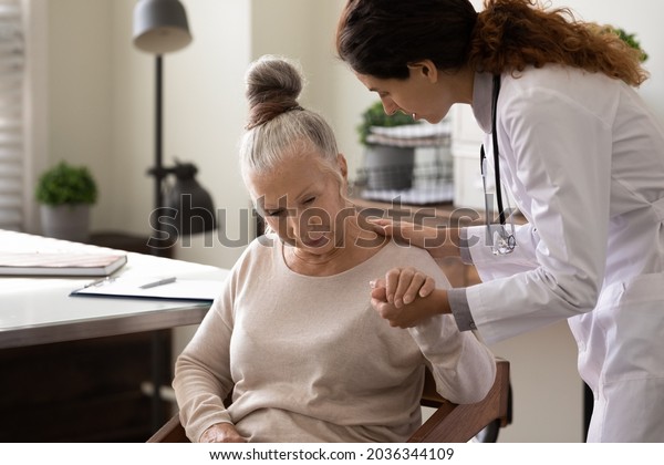 Serious young\
doctor helping elder patient to cope with bad news, serious\
diagnosis, holding hand of woman, giving comfort, support, empathy.\
Medic care, geriatric health care\
concept