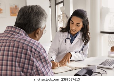 Serious young doctor woman writing down patients complaints, listening to older man visiting practitioner office, giving medical consultation, recommendation for checkup, treatment - Powered by Shutterstock