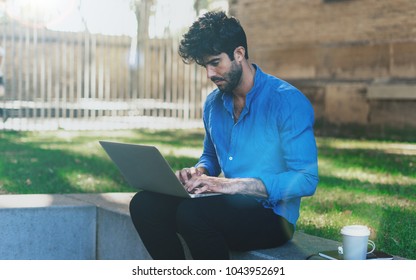 Serious Young Entrepreneur Preparing Presenation On A New Product On A Laptop For The Meeting With The Investors. Office Worker Reading Company News In Intranet While Having Coffee Break Outdoors.